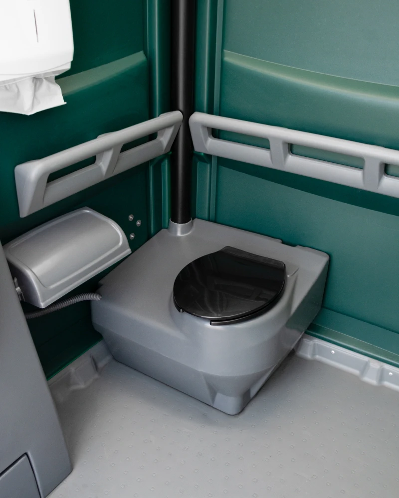 Innendetail des Komfort-WCs: WC-Sitz mit beidseitigen Haltegriffen für barrierefreie Nutzung und Klopapierhalter.