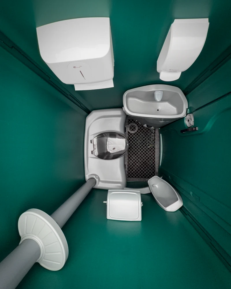 Innenansicht des Standard-Bauklos von oben mit WC-Becken, Waschbecken, Klopapierhalter und Seifenspender.